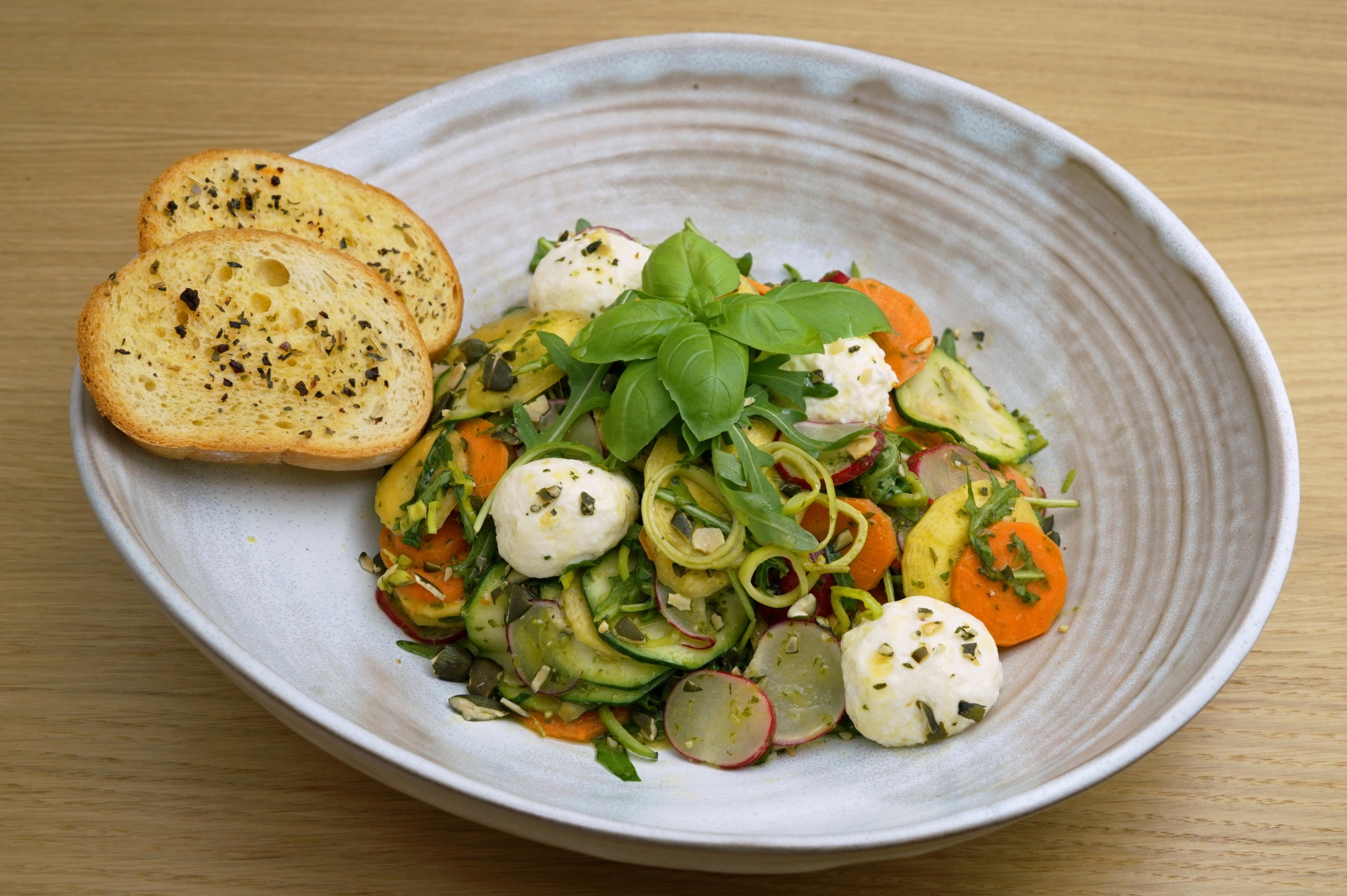 Gemüse[-]salat mit Kräuter-Kürbis[-]kern-Dressing und Frisch[-]käse[-]bällchen